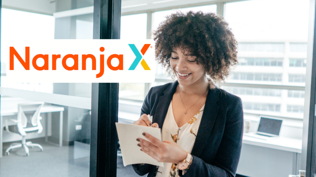 Mujer sonriente en oficina escribiendo en una libreta con el logo de Naranja X visible, promoviendo los Préstamos Personales Naranja X como una solución financiera rápida y flexible.