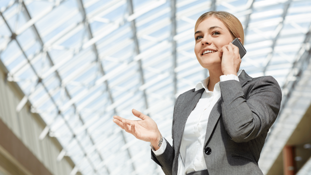 Mujer de negocios hablando por teléfono móvil mientras analiza el mercado inmobiliario en Argentina, con un fondo moderno y luminoso.